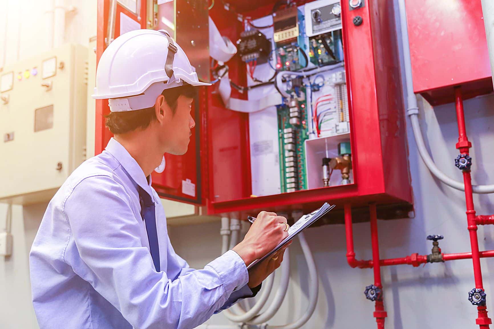 A fire protection engineer documenting an inspection of an industrial fire alarm or suppression panel