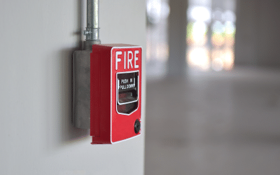 Red manual fire alarm pull station mounted on a wall, representing Summit Companies' fire alarm services