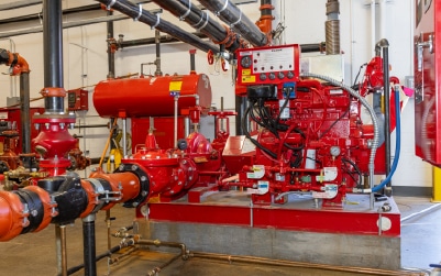 Industrial fire pump equipment with red housing and overhead metal piping.