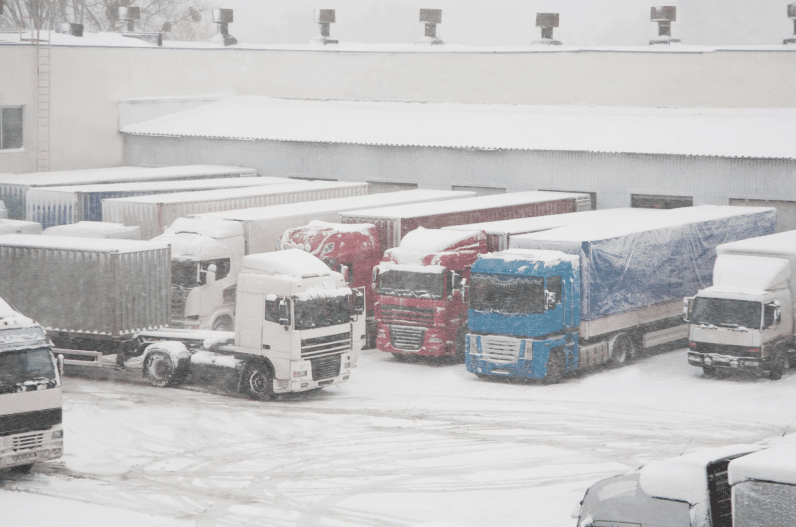 Snow-covered trucks parked at the loading dock of a warehouse, an area that might use an antifreeze loop for fire suppression.